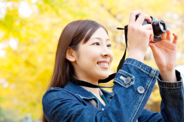 Kadın parkta kamerayla fotoğraf çekiyor.