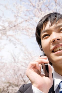 Genç Asyalı işadamı cep telefonuyla konuşuyor.