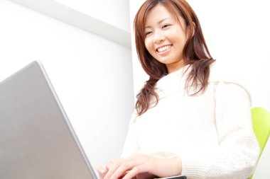 Young Japanese woman using laptop on white background 