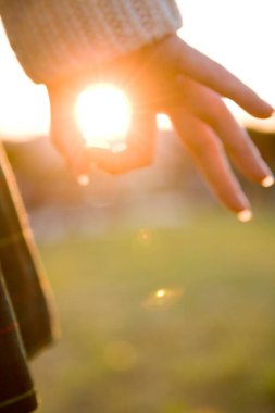 Kadın eli güneşin ışığını tutuyor 