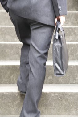 Evrak çantalı bir iş adamı merdivenlerden çıkıyor.