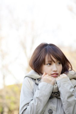 Genç güzel Asyalı kadın sonbahar parkında poz veriyor.