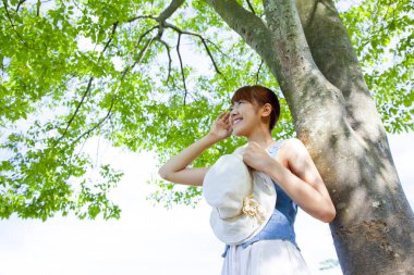 Ağacın altında şapkası olan Asyalı kadın.