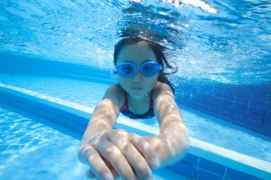 Mayolu ve gözlüklü bir kız havuzda yüzüyor.