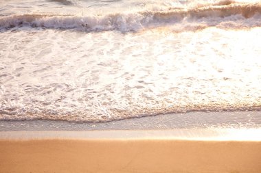 Kumsalda gün batımında deniz dalgaları, yaz tatili konsepti.