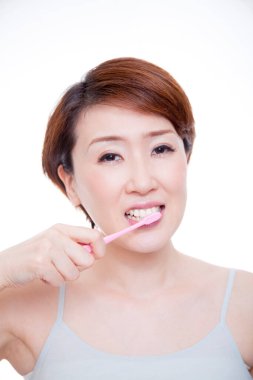 Olgun Japon kadın beyaz arka planda dişlerini fırçalıyor.