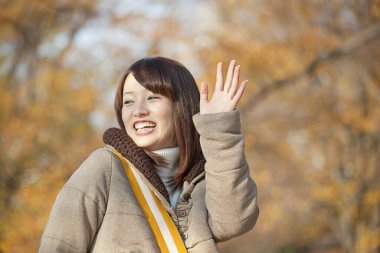 Genç güzel Asyalı kadın sonbahar parkında poz veriyor.