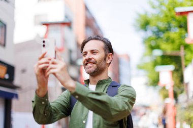 Kafkas adam cep telefonuyla antik Japon tapınağında fotoğraf çekiyor.