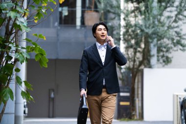 Şehirde telefonla konuşan yakışıklı bir işadamının portresi.