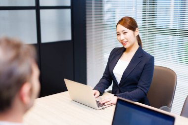 Modern ofis binasında dizüstü bilgisayarda çalışan güzel bir Japon kadın.