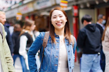 Sokakta yürüyen Japon kadın. Bagajlı çekici bayan turist şehrin cazibesine bakıyor.