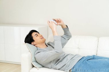 Genç Asyalı adam akıllı telefon kullanıyor. 