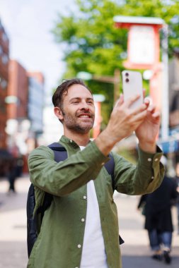 Kafkas adam cep telefonuyla antik Japon tapınağında fotoğraf çekiyor.