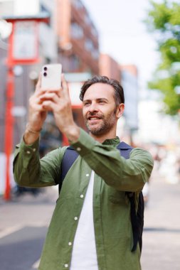 Kafkas adam cep telefonuyla antik Japon tapınağında fotoğraf çekiyor.