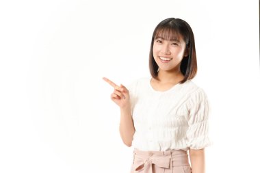 Güzel genç Japon kadın boş fotokopi alanını işaret ediyor ve gülümseyen yüzüyle kameraya bakıyor ve mutlu bir şekilde izah ediliyor. 