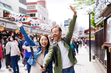 Kafkas erkek ve Japon kadın eski Japon caddesinin arka planında selfie çekiyorlar.
