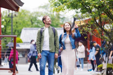 Güzel bir Japon kadın caddedeki Kafkasyalı turist için yol tarifi ve gezi hakkında bilgi veriyor.
