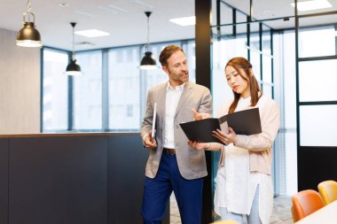 Yakışıklı beyaz adam ve güzel Japon kadın modern ofiste birlikte çalışıyorlar.