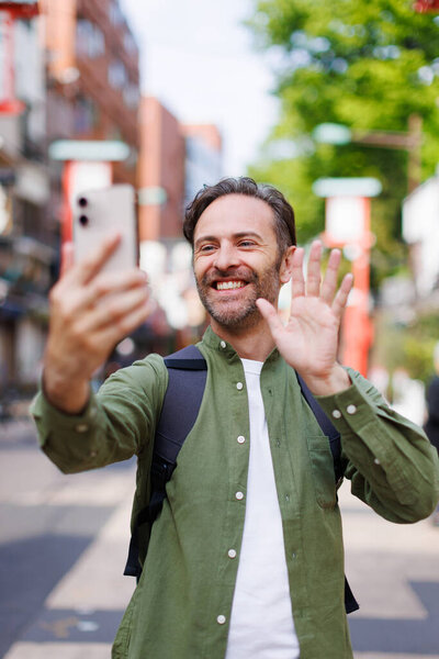 Young caucasian man in green shirt taking selfie with mobile phone