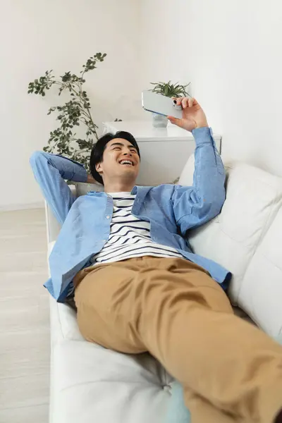 young man with phone on sofa at home