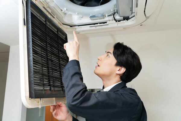 young asian man repair air conditioning unit at home.