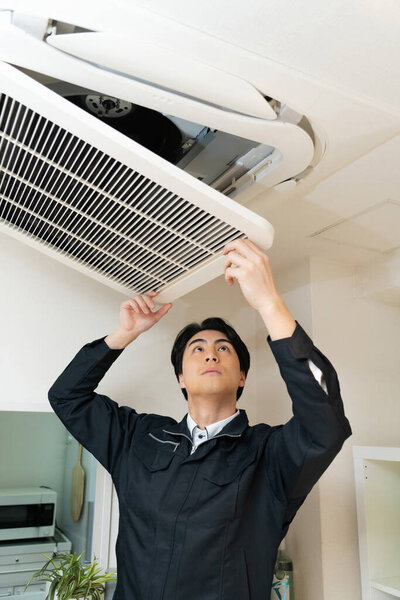 asian man installing air conditioning on the ceiling 