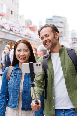 Kafkas erkek ve Japon kadın eski Japon caddesinin arka planında selfie çekiyorlar.