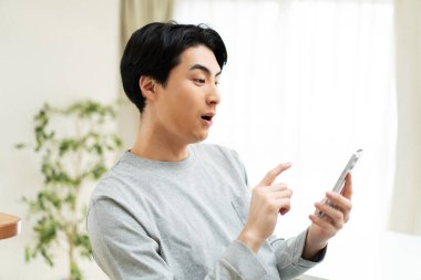 Genç Asyalı adam akıllı telefon kullanıyor. 