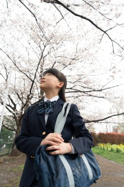 Parkta okul çantalı Asyalı kız.