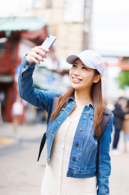 Japon kadın sokakta selfie çekiyor. Şehirde fotoğraf çeken çekici bir bayan turist. 