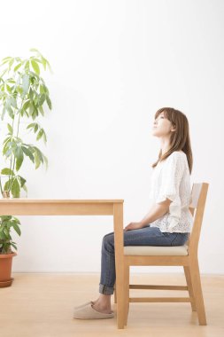 Evdeki ahşap masada oturan genç kadın.