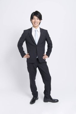 Beyaz arka planda siyah takım elbiseli genç Asyalı iş adamı