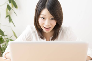 Evde dizüstü bilgisayarda çalışan Asyalı kadın.