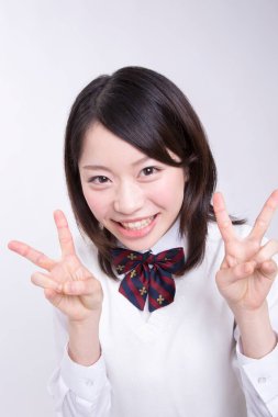 Genç Asyalı öğrenci zafer işaretleri gösteriyor.