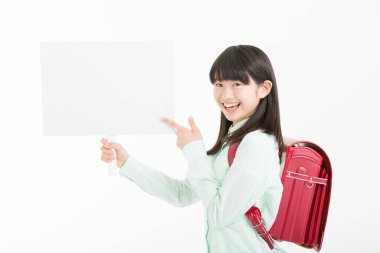 Genç Asyalı kız öğrenci beyaz arka planda izole edilmiş boş kart gösteriyor. 