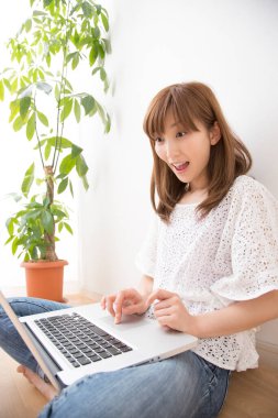 Evde dizüstü bilgisayarı olan gülümseyen güzel bir Japon kadın.