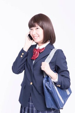 Akıllı telefondan konuşan gülümseyen Japon öğrencinin stüdyo portresi