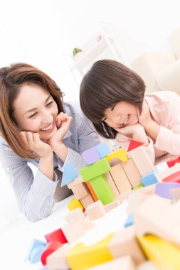 Asyalı anne ve küçük kızı birlikte oynuyorlar.