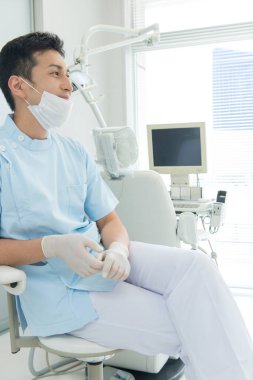 Maskeli bir adam sandalyede oturuyor.