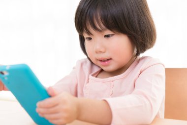 Küçük sevimli Asyalı kız telefon kullanıyor.