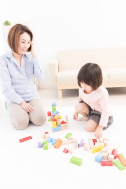 Asyalı anne ve küçük kızı birlikte oynuyorlar.