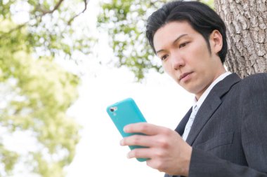 Parkta cep telefonu kullanan genç adam.