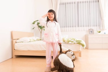 Küçük tatlı Asyalı kız evde oyuncak ayıyla oynuyor. 