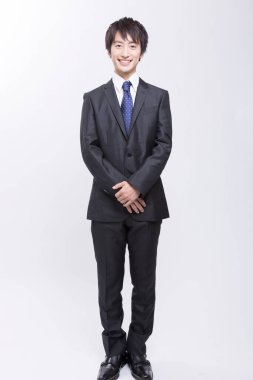 Takım elbiseli Asyalı işadamı stüdyoda duruyor.