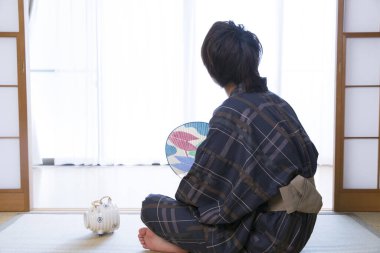 Etnik kaplıca otelinde geleneksel yukata giymiş yakışıklı Japon gencin portresi.