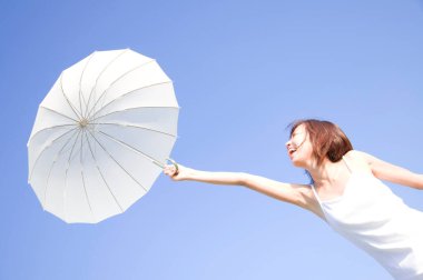 Güzel Asyalı kadın deniz kenarında şemsiyeyle poz veriyor.