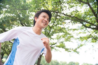 Sportif Japon adam yaz parkında koşuyor. 