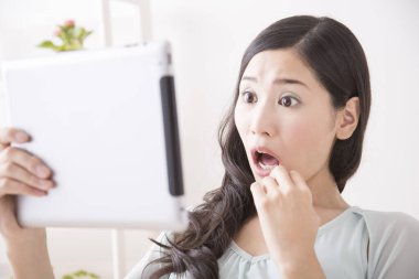 Şaşırmış Asyalı kadın tablet bilgisayara şaşırmış görünüyor. 