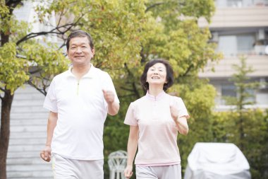 Asyalı bir adam ve kadın kaldırımda koşuyorlar.