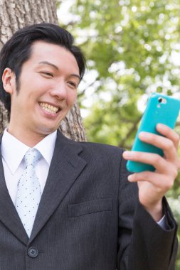 Parkta cep telefonu kullanan genç işadamı 